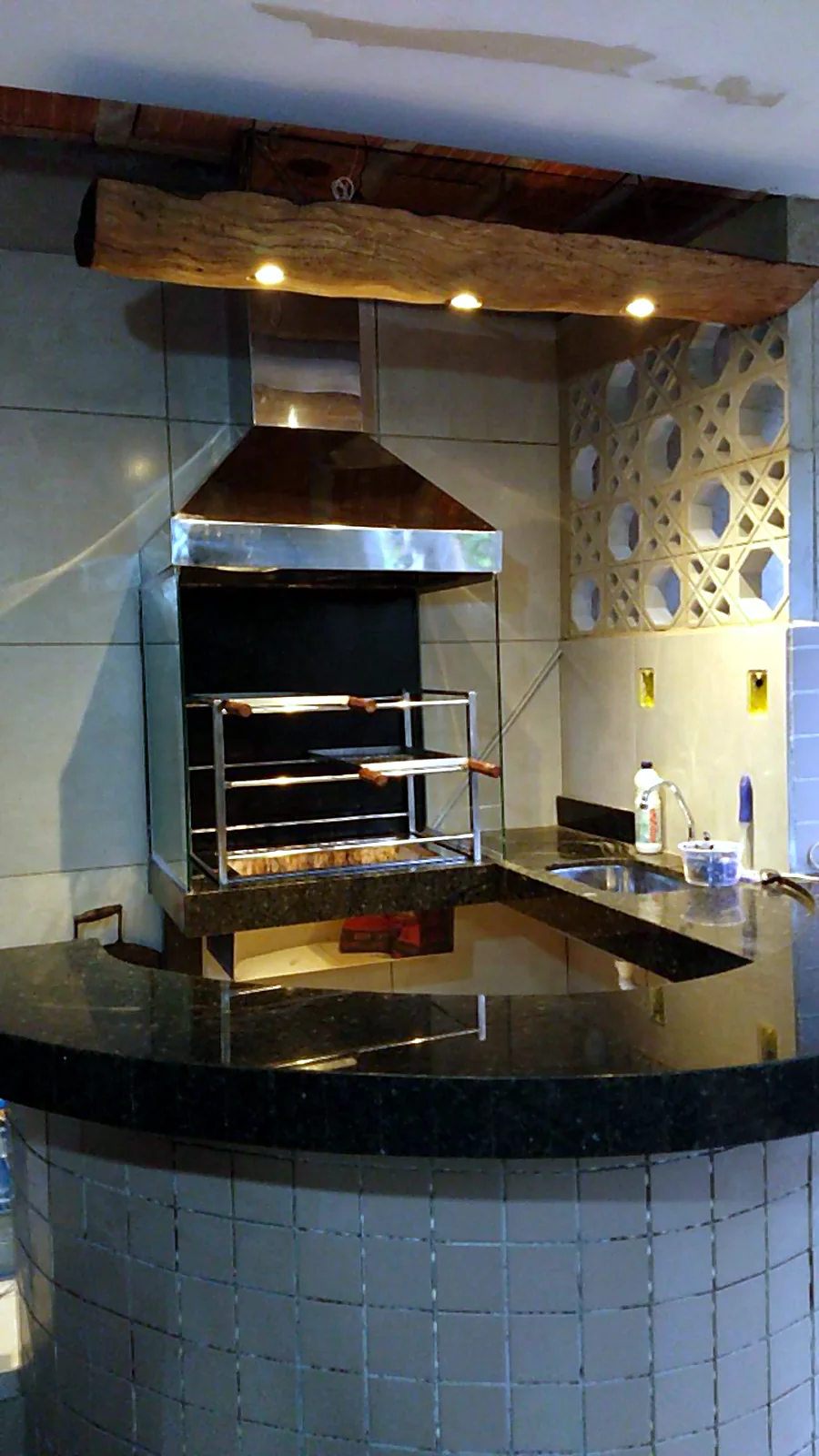 Área gourmet com churrasqueira e coifa em aço inox