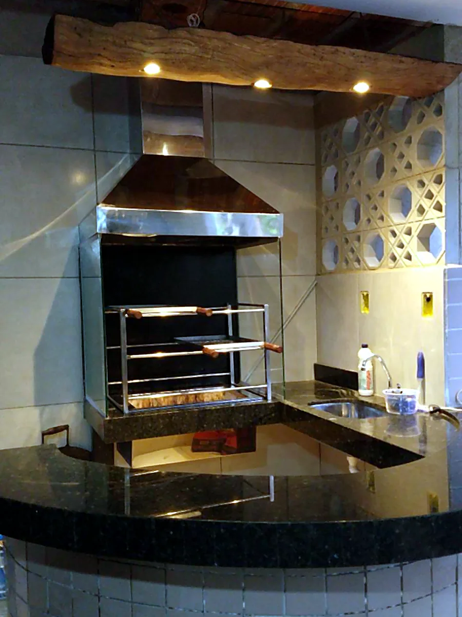 Área gourmet com churrasqueira e coifa em aço inox sob medida