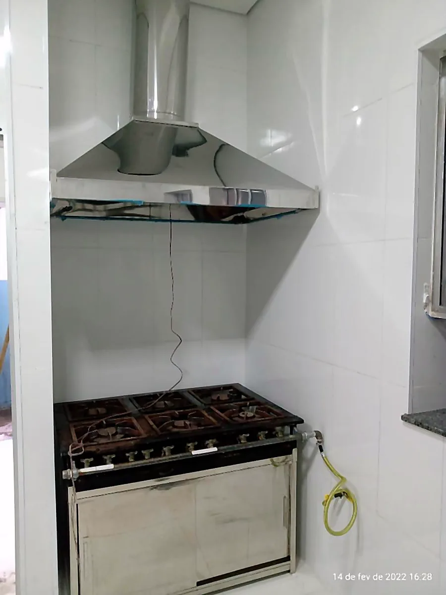 Coifa de inox instalada sobre fogão em cozinha residencial
